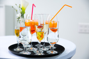 Rows of glasses with orange drink and ice cubes