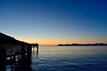 Fototapeta na wymiar Sunrise over palma de port de pollensa beach in Mallorca, Spain with jetty / pier 