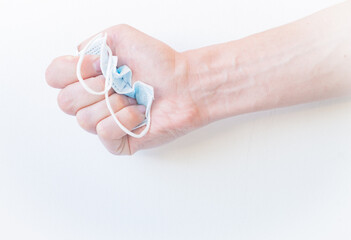 Crush the medical blue disposable mask on a white background with your hand