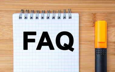 Business concept. On the wooden table is a marker and a notebook with the inscription FAQ -...