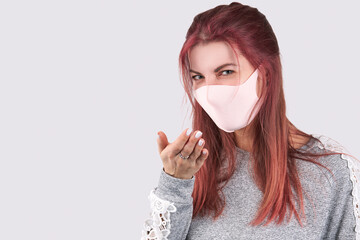 young caucasian woman  sneezes or coughs girl wearing face mask and dressed with casual clothes. isolated over gray background with copy space.