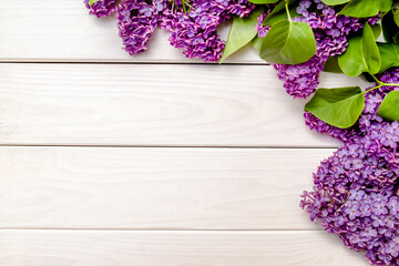 A bouquet of lilacs lies on a white wooden background
