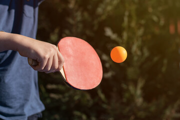 A boy playing table tennis, ping pong outside in the garden.
