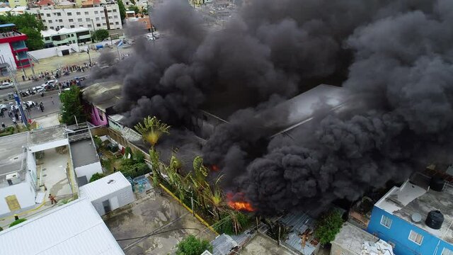 Aerial orbit, drone shot around a building fire, a big black smoke cloud rising from a burning structure, in Abuja, Nigeria, Africa