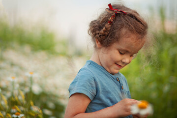 Portrait of a curly girl on the chamomile field