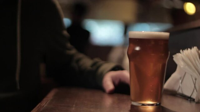 Waitress serves a glass of craft beer to client at a bar/pub.