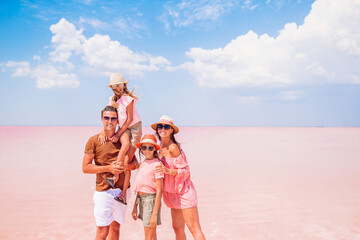 Family walk on a pink salt lake on a sunny summer day.