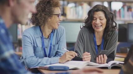 Female teacher helping mature woman student studying and using mobile phone in library learning IT skills in evening class - shot in slow motion - Powered by Adobe