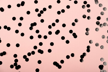 Rose color pastel festive background with holographic black confetti. Flat lay style with copy space for text, design. Trendy Holiday concept. Perfect pink backdrop for social media, blog, postcard.