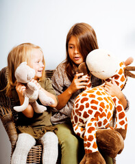 two cute sisters at home playing, little smiling girl in house interior on sofa, messing hair,...