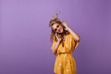 Inspired shapely woman smiling on purple background. Blithesome caucasian girl in orange clothes expressing happiness.