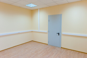 An empty room with a metal door and no windows.