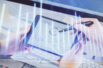 Double exposure of man's hands holding and using a phone and financial chart drawing. Market analysis concept.