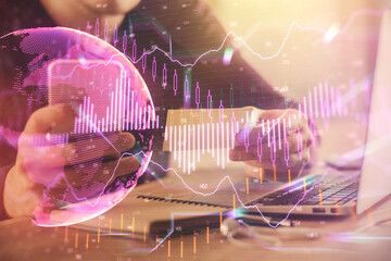 Double exposure of man's hands holding and using a phone and financial graph drawing. Analysis concept.