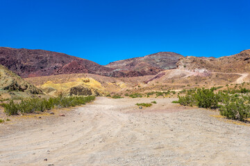 A dirt road in the Odessa Canyon area near Yermo, California, in the Mojave Desert with colorful mountains.