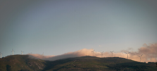 green mountain landscape with electric windmills and fog