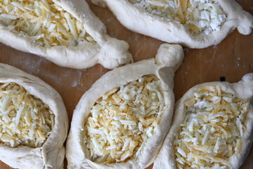 Selective focus. Adjarian khachapuri before baking. Fresh homemade khachapuri with cheese filling. Georgian cuisine. Cheese bread.