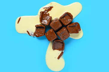 half melted chocolate blocks with vanilla flavor ice cream inside on blue background