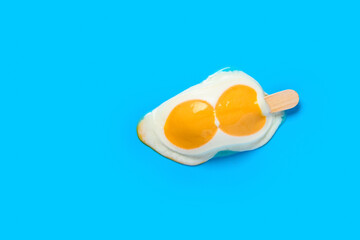 top view egg shape popsicle starts melting on blue background