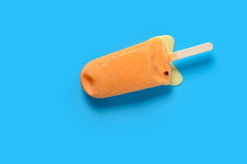 top view orange color chocolate outer popsicle with beans inside starts melting on blue background