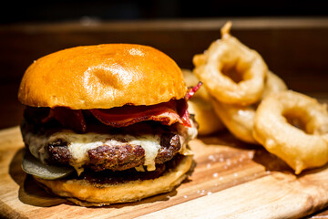 hamburger on a wooden table with onion rings, pub food