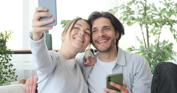 Couple taking selfie using mobile phone camera at home