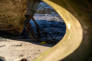 Ropes and chains of old dingy boat on the sandy shore line
