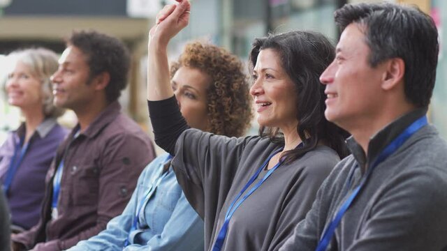 Businesswoman in presentation at conference raising hand to ask question - shot in slow motion