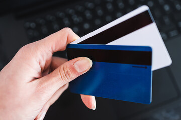 online shopping or internet banking, hand holding payment cards with laptop keyboard in the background