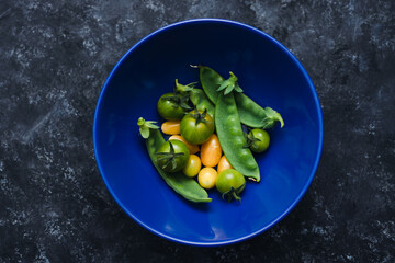 simple food ingredients, bowl with freshly picked snowpeas and tiny yellow and green tomatoes for vegetable roast