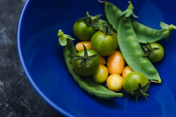 simple food ingredients, bowl with freshly picked snowpeas and tiny yellow and green tomatoes for vegetable roast