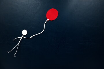 Human stick figure flying with a red balloon in dark background.