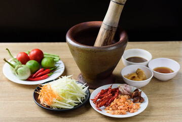 Thai cuisine, food ingredients and recipe for spicy papaya salad (Som Tum) on wooden table