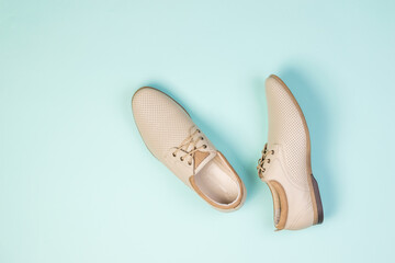 Top view of a pair of light summer men's shoes on a light blue background.