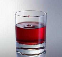 Drop is splashing in glass. Red wine drop hovered in the air