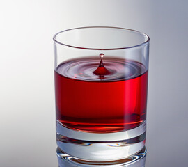 Drop of red wine in glass close up. High speed shot. Waves in glass.