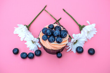 birthday cake decorated with large blueberries and flowers on a pink background