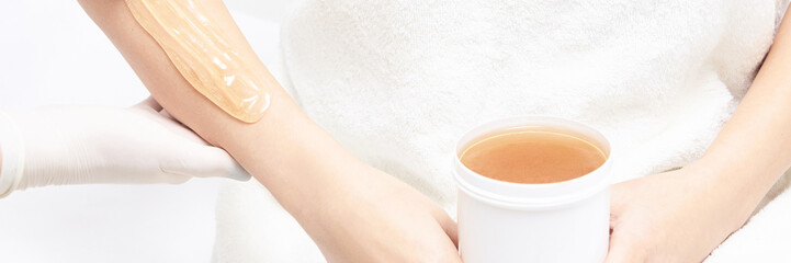 Hot hair removal depilation. Female skin routine. Sugar bodycare. Wax correction. Professional cosmetologist help girl. Sugaring bodycare cosmetics. Hand epilation with bowl. Horizontal banner