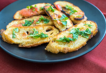 Sourdough bread fried in garlic and olive oil with squeezed tomato and chopped basil on top.