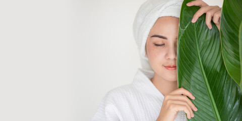 Beautiful woman in the spa salon, relaxation of Asian woman in spa dress with natural leaf on grey...