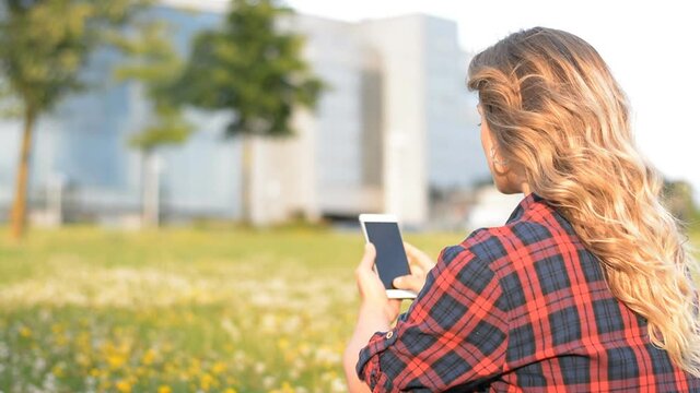 college hipster girl text messaging mobile phone in the park