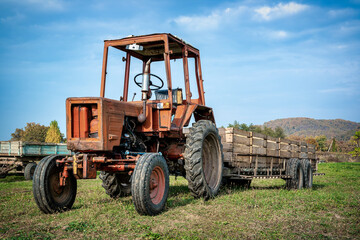 An old rusted tractor with a trailer on farm