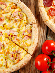 Pizza with pineapple on a wooden background, close-up, cherry tomatoes