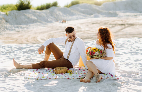 Beautiful picnic on the sand near the lake in summer. Beautiful young couple