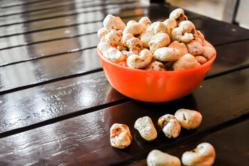 Popcorn in an orange bowl on wooden table