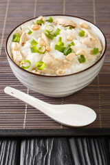 Ginger chicken Jook Rice Porridge close-up in a bowl on the table. vertical