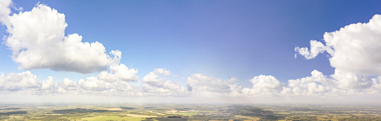 Fototapeta premium summer rural landscape under blue sky with fluffy clouds. panoramic aerial view of picturesque agricultural fields 