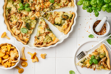 Homemade lorraine quiche or pie with chicken, broccoli and chanterelles on a white background. Tart with meat and mushrooms. Top view © Olga Romankova