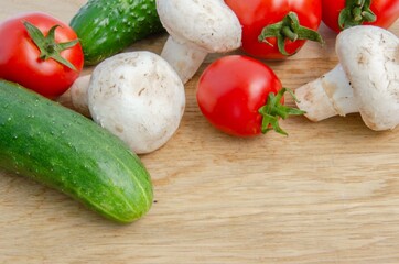Tomatoes cucumbers mushrooms. Fresh summer vegetables and white mushrooms. Red and green vegetables background.