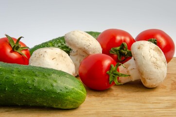 Tomatoes cucumbers mushrooms. Fresh summer vegetables and white mushrooms. Red and green vegetables background.